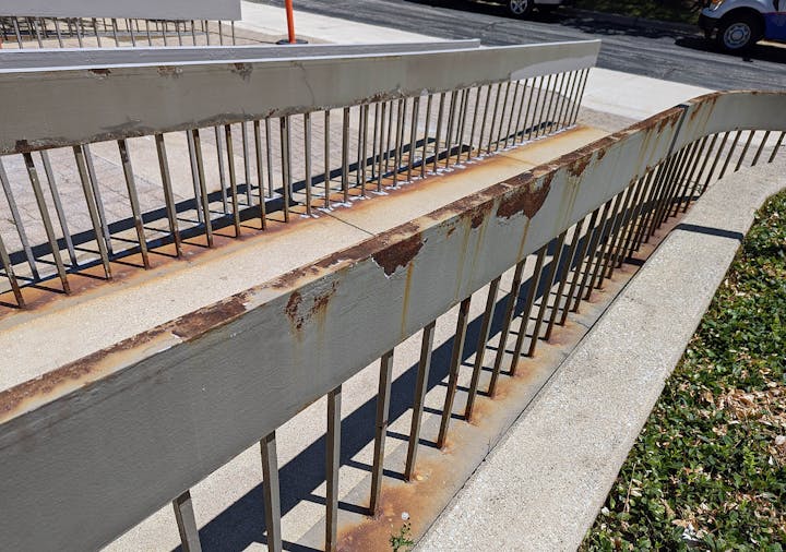 Rust and peeling paint on exterior metal handrail