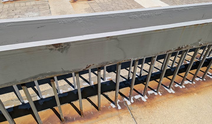 Cleaning and prepping rusted metal railing for repainting.